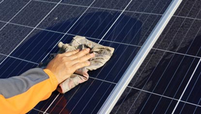 Hand with cloth cleaning solar panels