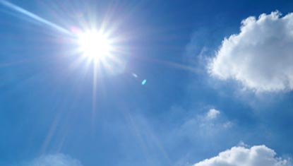 Sun shining in a blue sky, with some clouds.